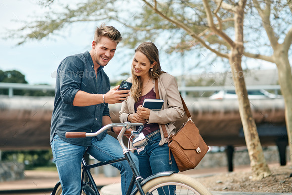 Shot of two young students using a mobile phone outside on campus - Stock Photo - Images