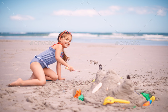 Building the castle of her dreams. Portrait of a little girl building a sandcastle at the beach.