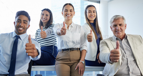 We love what we do. Shot of a group of businesspeople showing thumbs up at the office.
