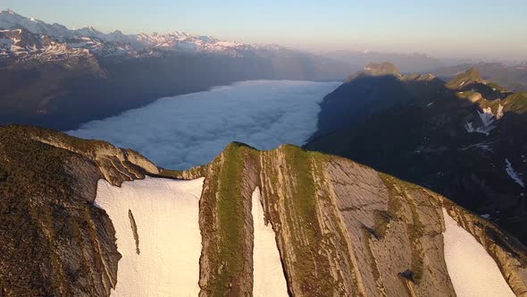 Revealing Aerial Shot Of A Sea Of Fog In The Swiss Mountains During Sunrise alt