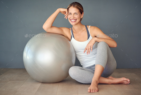 Lets play ball. Shot of a sporty young woman sitting next to her fitness ball.