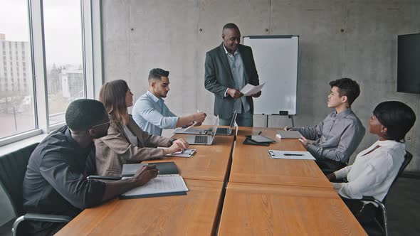 African Mature Male Boss Mentor Leader Coach Standing in Office Boardroom Giving Colleagues alt