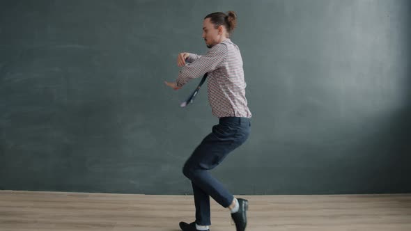 Flexible Guy Performing Funny Dance on Dark Gray Background Looking at Camera alt