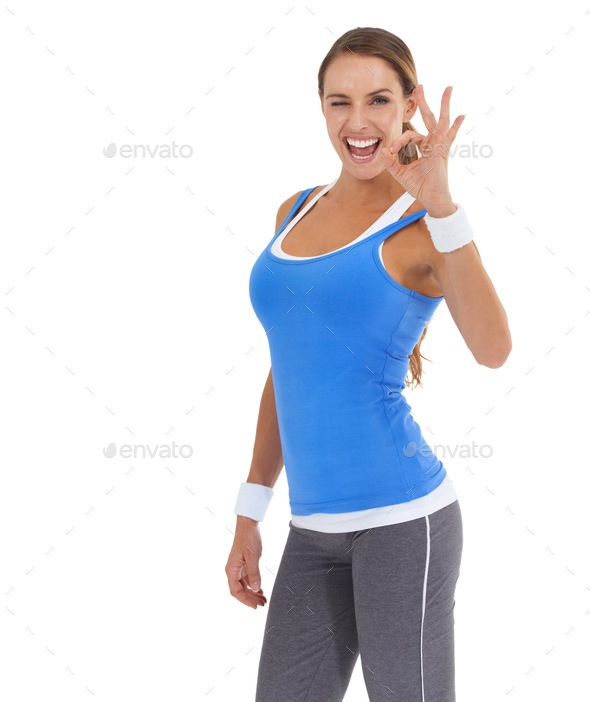 Feeling fit and fab. Fit young woman giving the ok gesture against a white background.