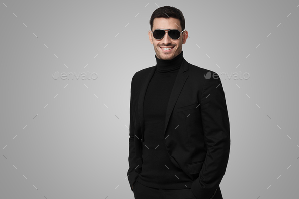 Serious body guard or secret agent wearing suit and sunglasses on gray background