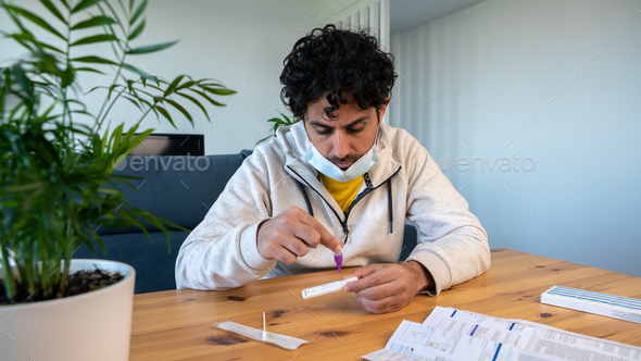 Man wearing mask placing the sample into the covid19 antigen test device at home