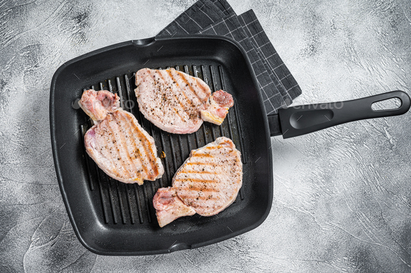 Fried on a grill skillet pork chop steaks. White background. Top view