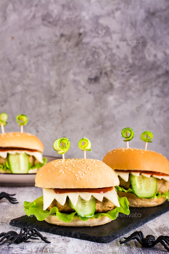 Monster burgers for halloween menu on slate and spiders. Home made creative food. Vertical view