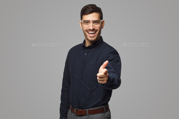 Portrait of European man pointing at camera as if choosing viewer for his project, isolated on gray