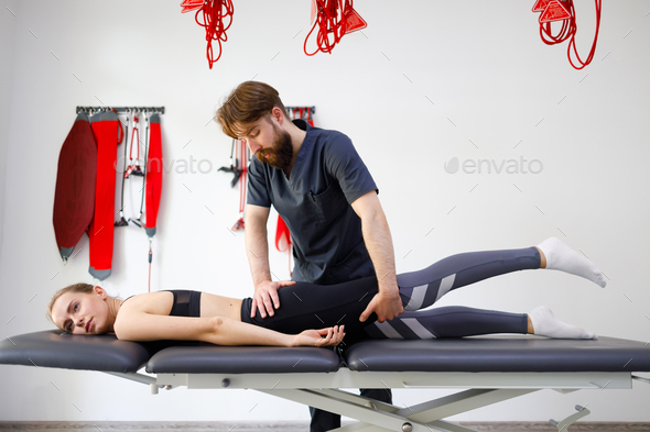 Chiropractor stretching the legs and hips of a young female patient. Diagnosis