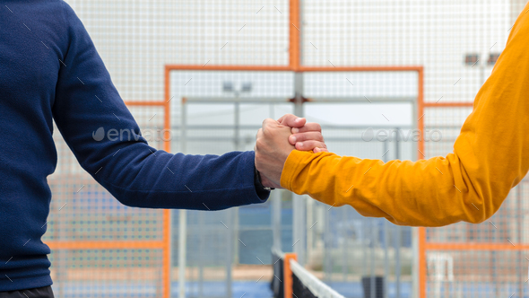 Male padel players handshake after win padel match in blue paddel court outdoor