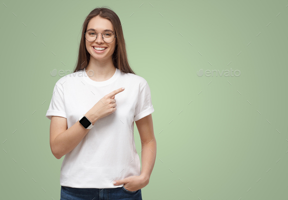 Pretty girl pointing right, looking excited, isolated on green copy space background - Stock Photo - Images