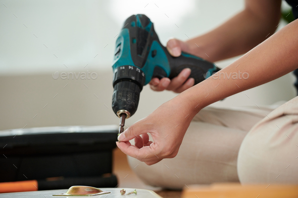 Girl using drill to make repair