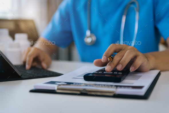 Doctor with calculate medical fee costs and revenue.  - Stock Photo - Images