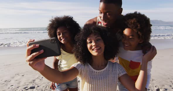 African american parents and their children taking a selfie with smartphone on the beach alt