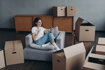 Girl blogger greeting followers in social networks, sitting with boxes for relocation on moving day