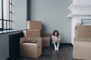 Sad woman sitting on the floor among carton boxes with things for moving. Divorce, eviction concept
