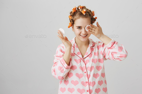 Maybe I do not see but hear. Portrait of cute funny european female in hair curlers and nightwear