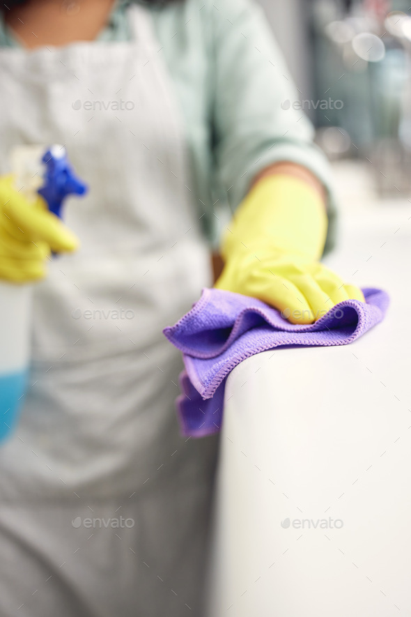 Nothing escapes this rag. Shot of a woman using a spray bottle and cloth while cleaning a counter.