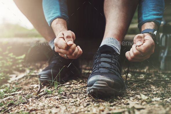 Close up shot of an unrecognizable man tying up his shoe laces on a hiking trail