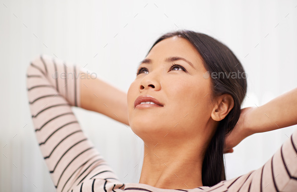 Shot of an attractive asian businesswoman leaning back with her arms behind her head