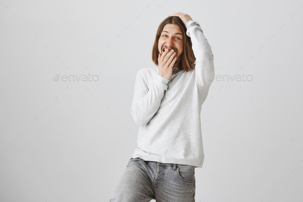 Emotive boyfriend cannot hide his happiness. Portrait of good-looking bearded guy with long hair