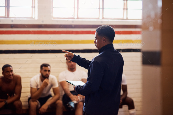 Shot of a rugby coach addressing his team players in a locker room