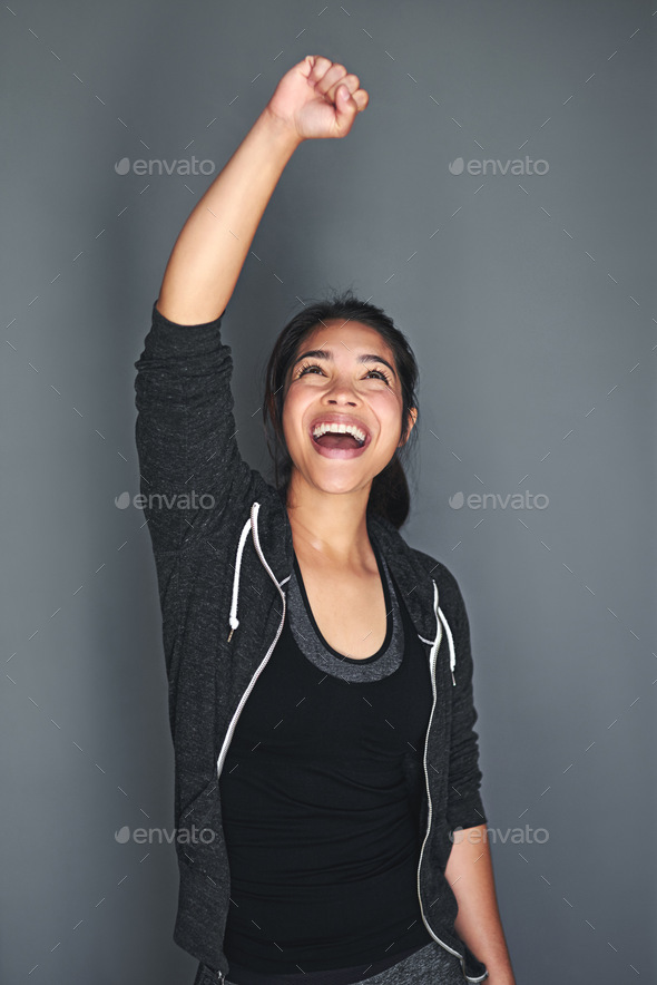 Shot of an excited young woman in sports clothing punching the air