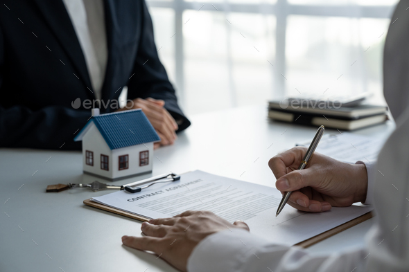 Real estate brokers point to a contract paper with her pen and advise customers to sign their names