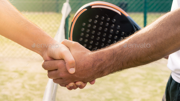 Male padel players handshake after win padel match in green paddel court indoor