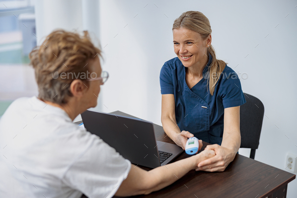 Doctor measures patient\'s temperature with non-contact thermometer during an appointment
