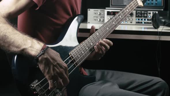 Musician records a bass guitar track in his own studio. alt