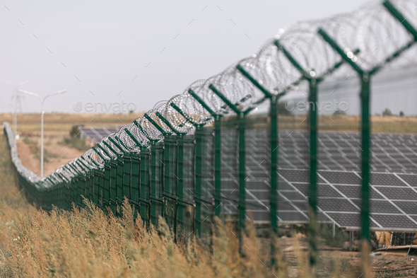 Solar power station protected from road by barbed wire fence. Fencing of sensitive sites with