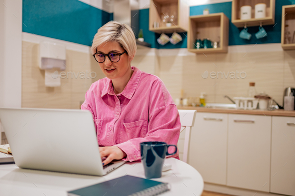 Woman working on a laptop in the kitchen at home