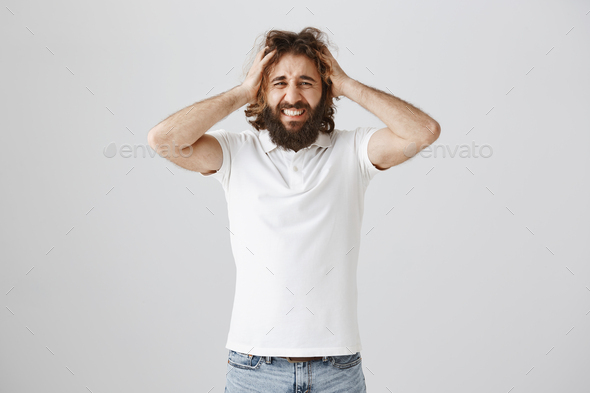 Headache mixed up thoughts. Stressed miserable eastern man with curly hair and beard holding head