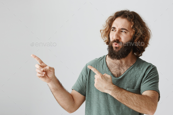 Man is impressed with cool sports car. Indoor shot of amazed bearded eastern guy with curly hair
