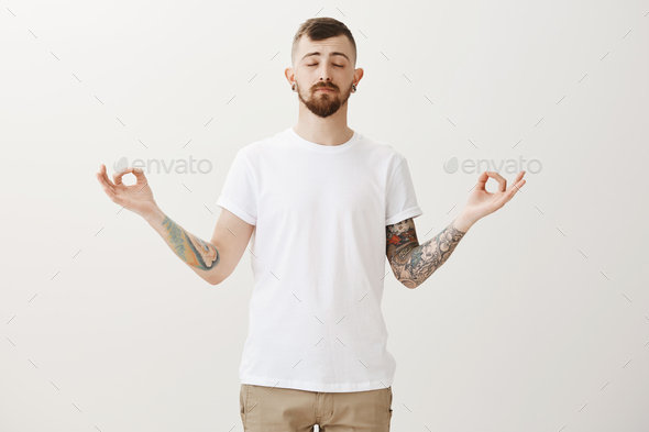 Need to stop and calm down. Portrait of relaxed good-looking urban guy with tattoos and beard