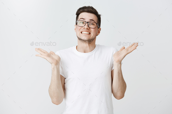I do not care sorry. Sandsome happy and carefree young european man in glasses shrugging smiling