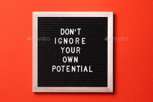 Motivational quote on black letter board on orange background. Don't ignore your own potential.