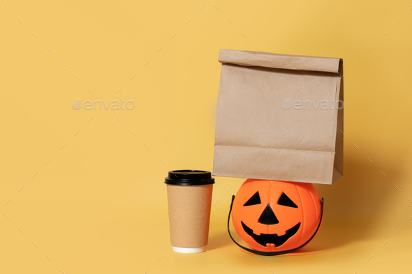 Halloween.Eco friendly paper coffee cup and pumpkin isolated yellow background,breakfast to go