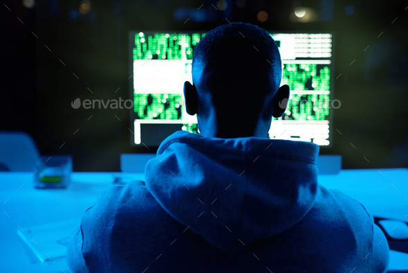 Rearview shot of a male hacker cracking a computer code in the dark