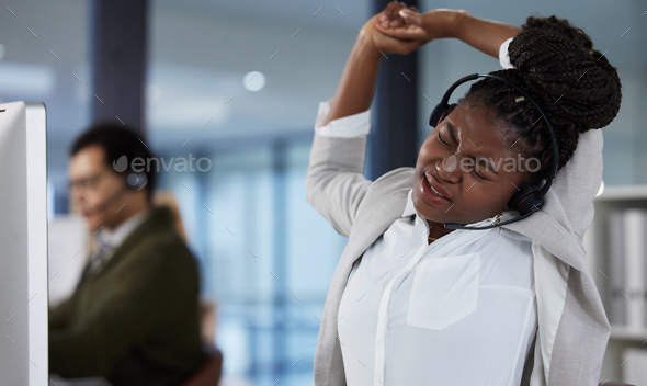 Shot of a young female call center agent stretching in an office at work