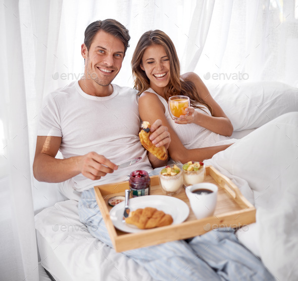 Nothing better than breakfast in bed. Shot of a loving young couple enjoying breakfast in bed.