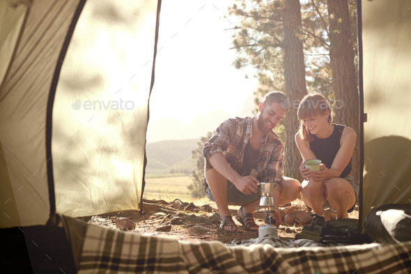 All the comforts. Shot of a young couple making coffee on a camp stove while camping.
