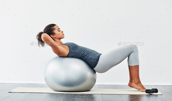 Work towards small achievements each day. Shot of a young woman exercising using a fitness ball.