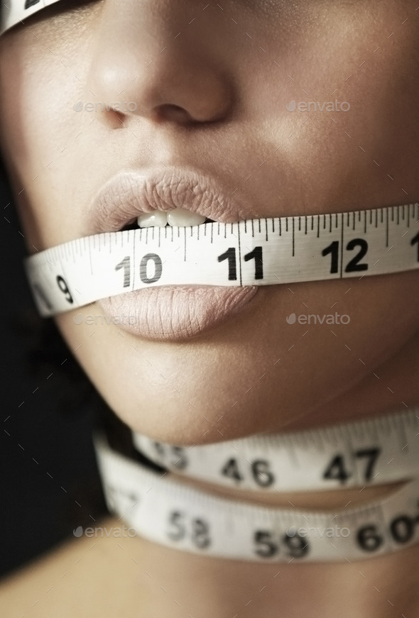 Concept shot of an anorexic woman with measuring tape wrapped around her head
