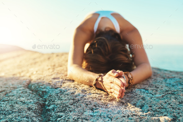 Bow down to the Gods. Shot of a young woman doing yoga at the beach.