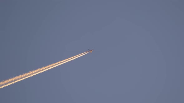 Distant Passenger Jet Plane Flying on High Altitude on Clear Blue Sky Leaving White Smoke Trace of alt