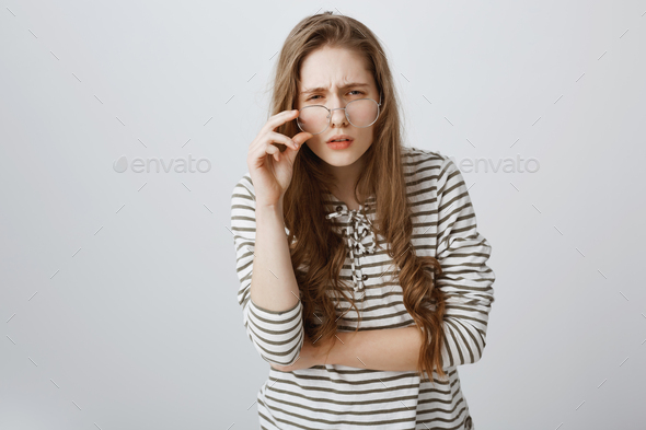 Girl cannot see clearly without glasses. Cute young teenager squinting and frowning, having bad