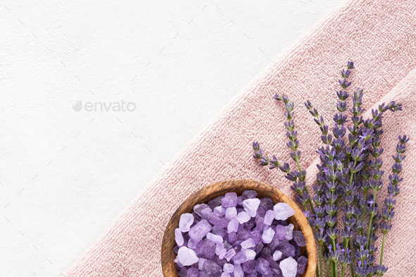Lavender flowers, bath salt and pink towels on light background. SPA, body care concept